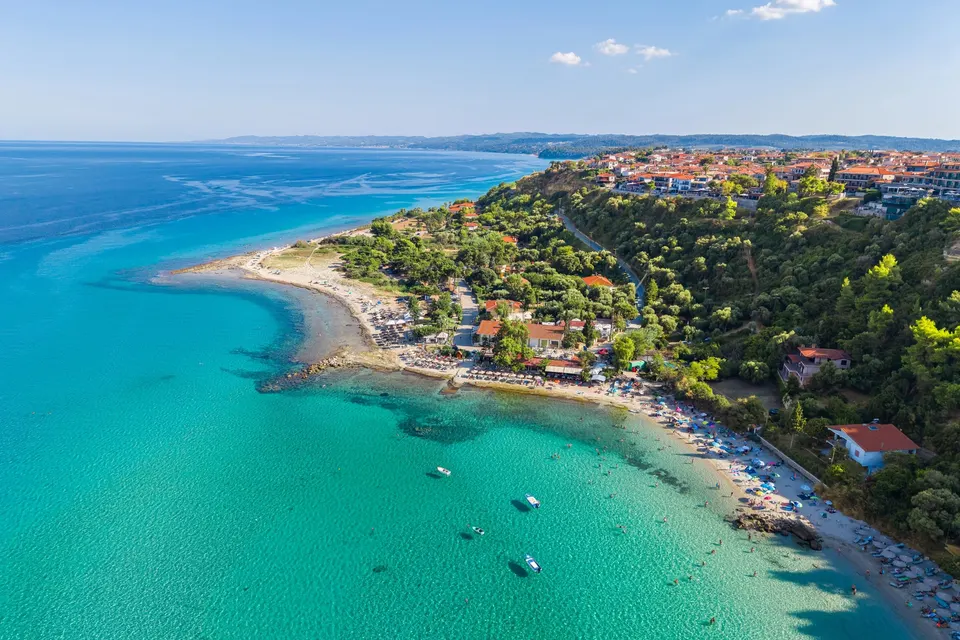 Afitos på klinten over sandstranden og det turkise vand, set fra luften