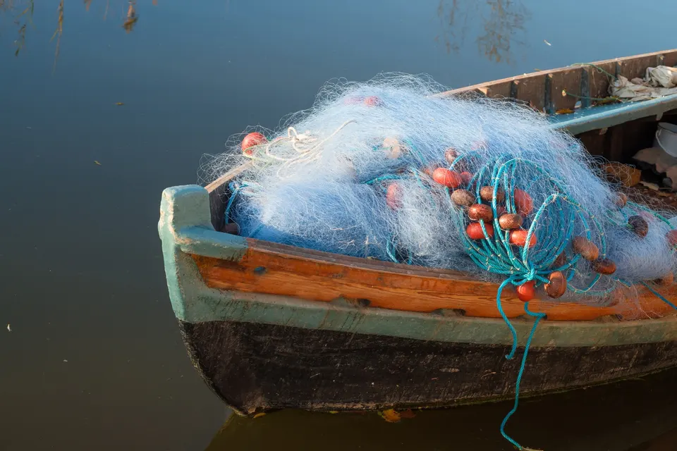Fiskerbåd med net liggende i roligt vand
