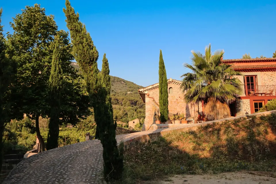Finca af sten med cypresser og palme i aftensol på Mallorca