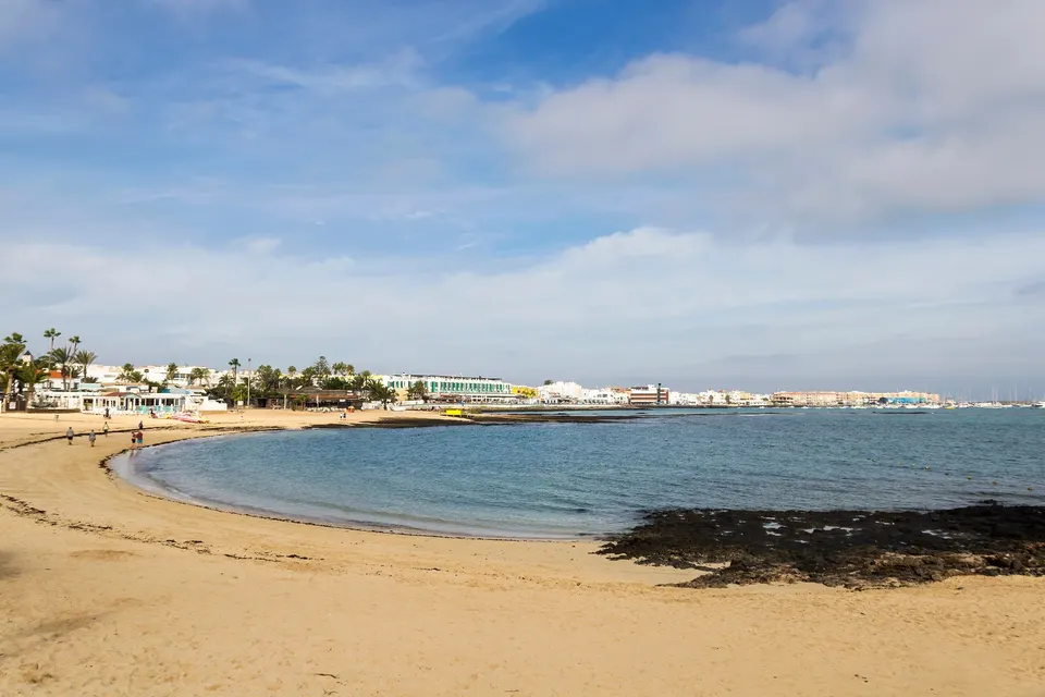 Strand med lavasten og byen Corralejo bagved