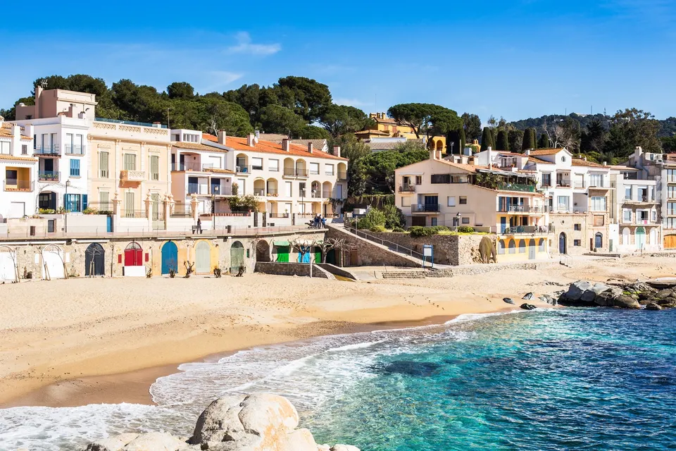 Calella de Palafrugell med hvide huse, buer og en lille sandstrand på Costa Brava