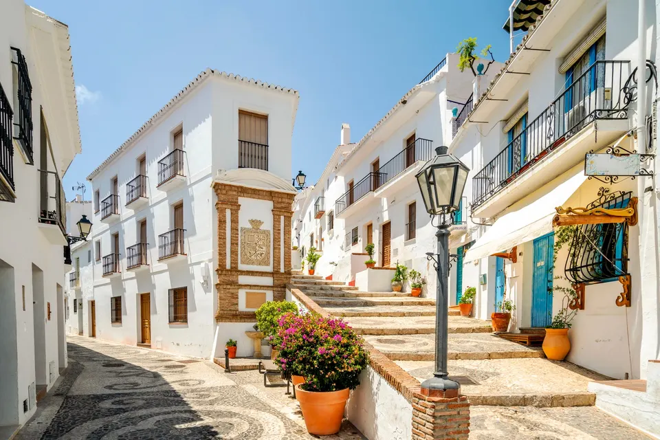 Trappegade med hvide huse, bougainvillea og blomsterkrukker i landsbyen Frigiliana på Costa del Sol