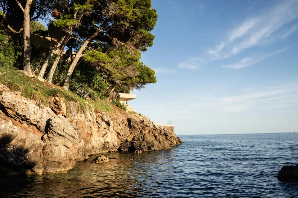 Klippekyst med pinjer og villaer over klart vand på Mallorca