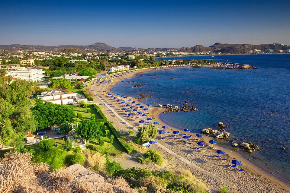 Faliraki-bugten set fra skråningen med den lange sandstrand og parasoller langs vandet