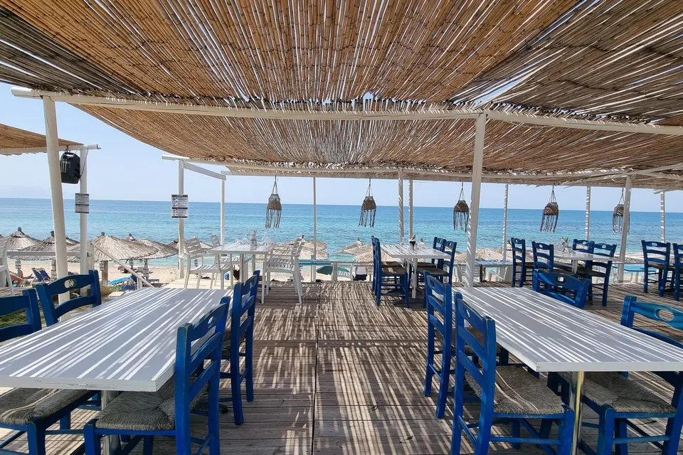 Strandtaverna med blå stole på stranden ved Kanali