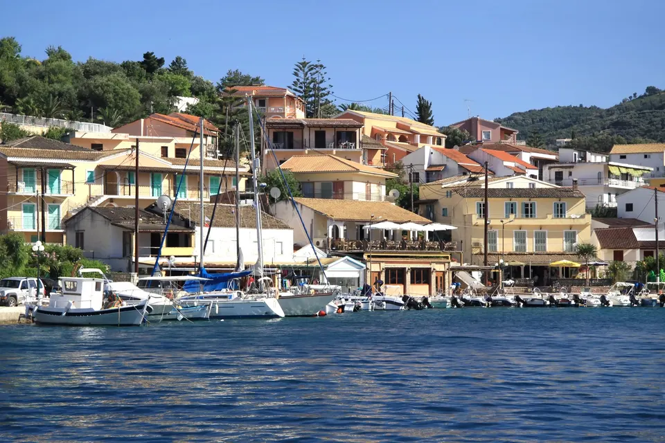 Kajen i Kassiopi med sejlbåde og gule og røde huse bag havnen