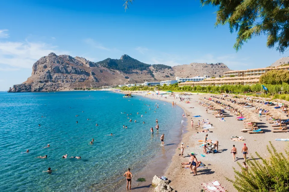 Sandstranden i Kolymbia med badende gæster og klippefremspringet mod nord