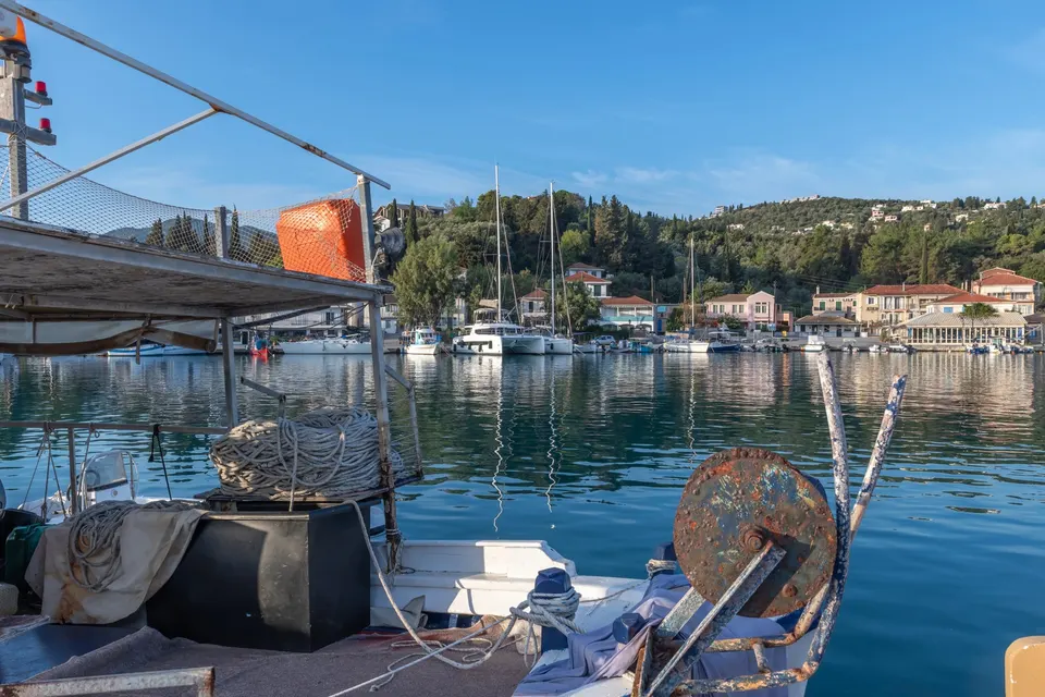 Havnen i Ligia med fiskerbåd og net i forgrunden og husene på havnefronten bag