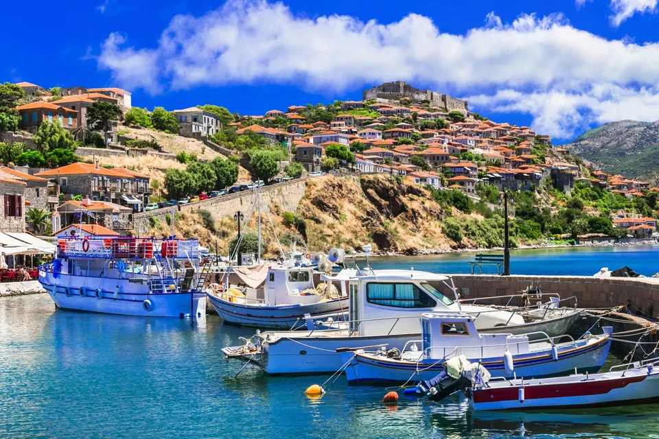 Havnen i Molyvos med fiskerbåde og borgen på bakken bag byen