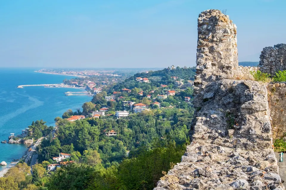 Udsigt fra en borgmur over en kystlinje med havet og byer i det fjerne