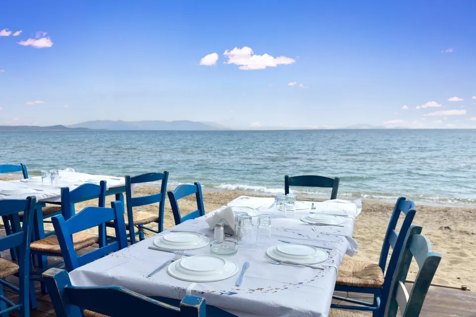 Tavernabord af træ på en sandstrand ved havet