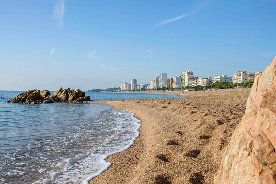 Stranden ved Platja d'Aro med klipper og byens huse i baggrunden