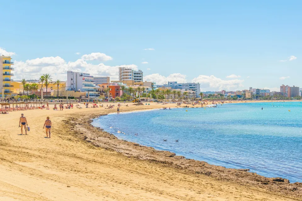 Den lange sandstrand Playa de Palma med hoteller langs promenaden og roligt, lavt vand
