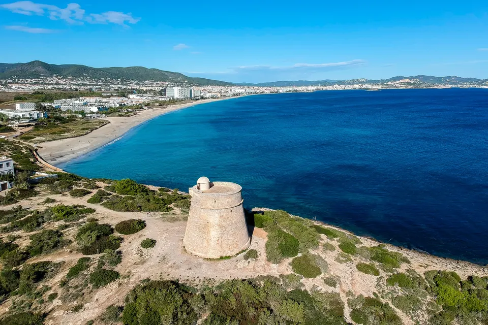 Den lange strandbue i Playa d'en Bossa set fra oven med turkis vand og hotellerne langs stranden