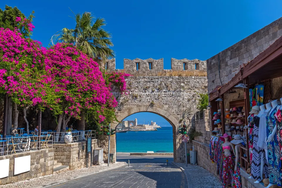 Porten i bymuren i Rhodos gamle by med bougainvillea og udsigt til havnen
