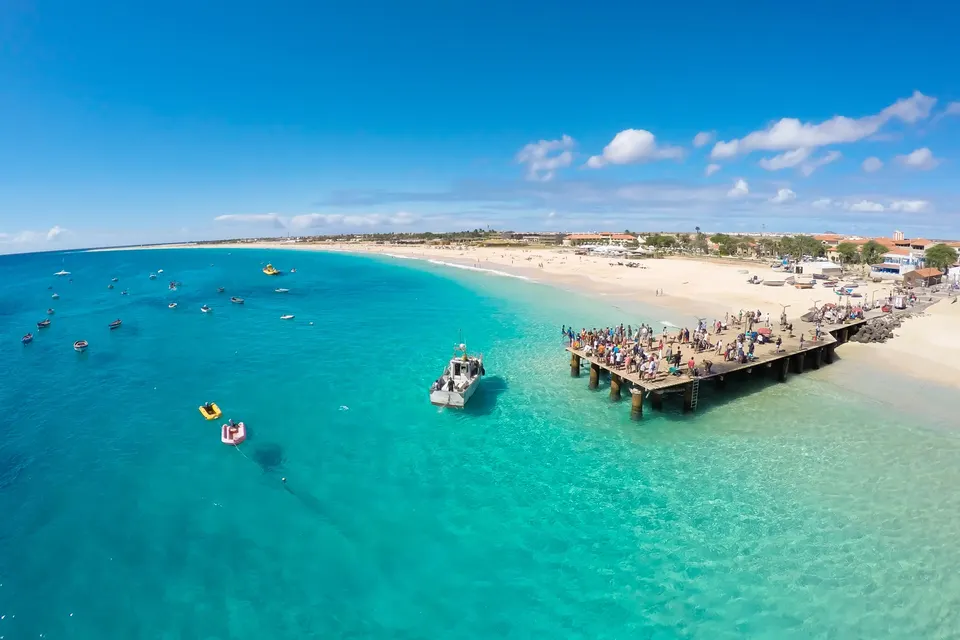Molen og den lange hvide strand i Santa Maria med både og badende set fra luften
