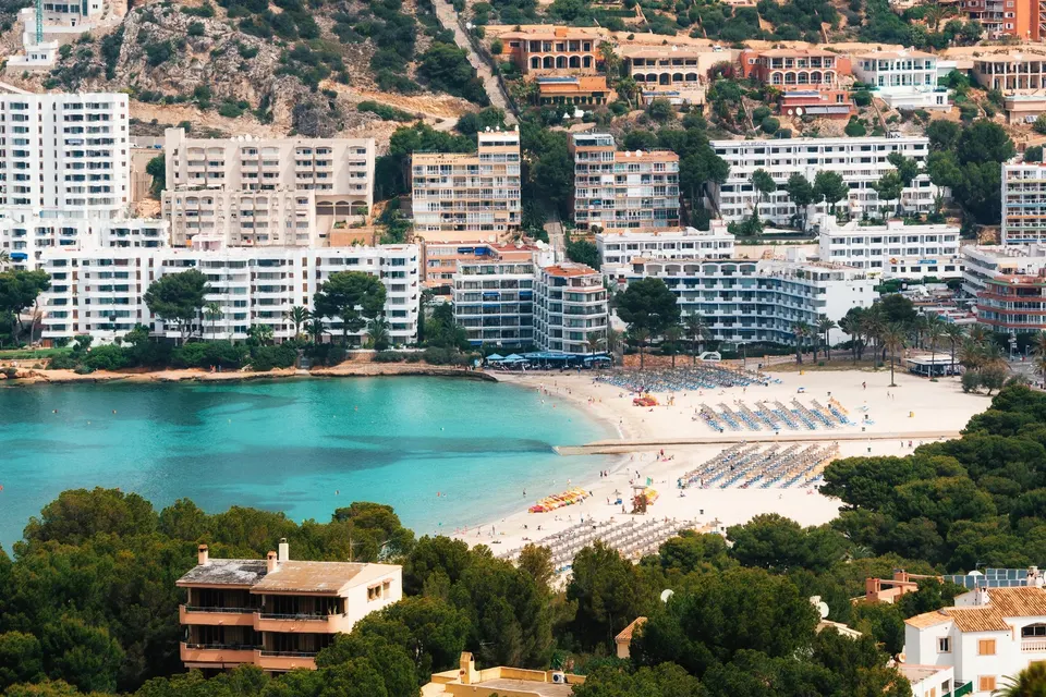 Luftfoto af Santa Ponsas sandstrand og turkis bugt med hvide hoteller og lejligheder bagved
