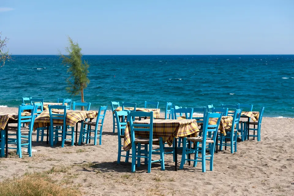 Blåt bord og stole på en sandstrand ved havet