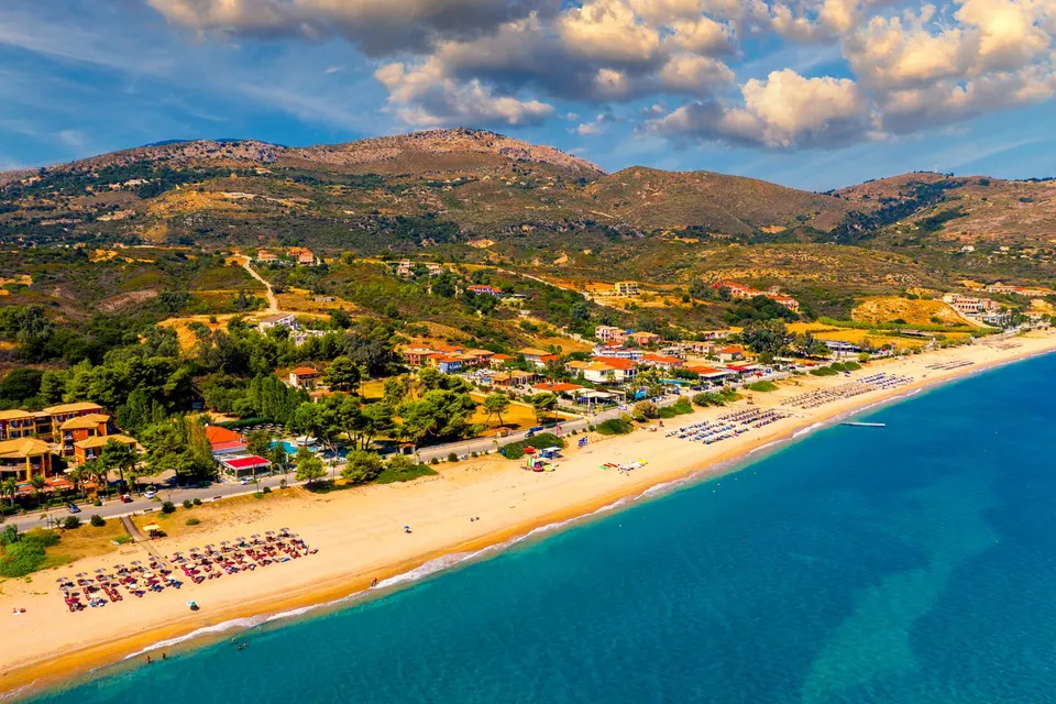 Skala-stranden og byen med bjergene bagved set lavt fra luften