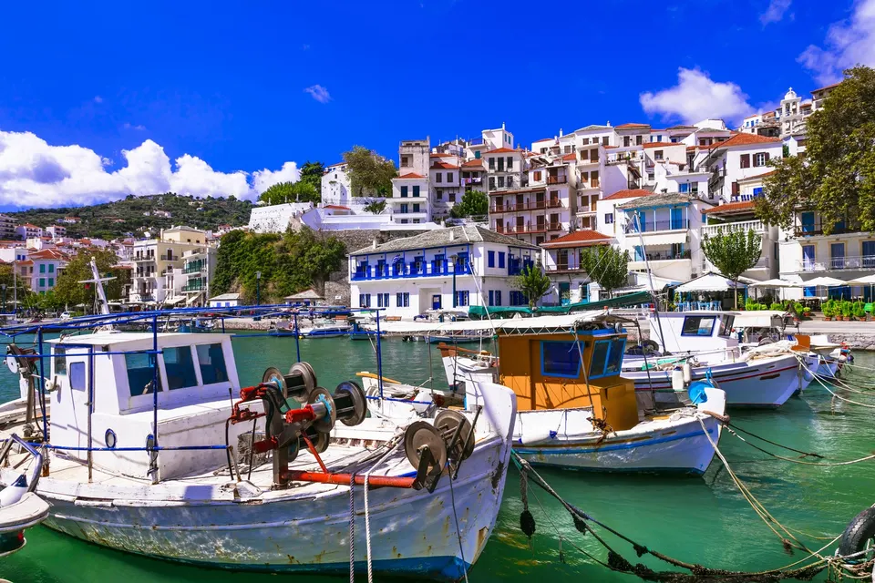 Fiskerbåde i den gamle havn i Skopelos by med hvide huse bagved