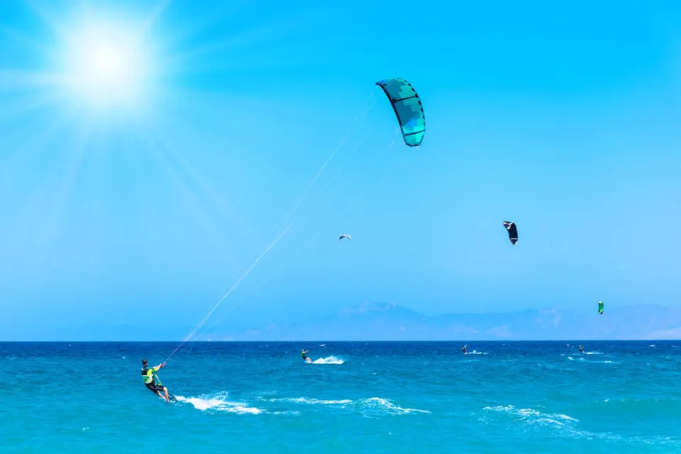 Kitesurfere i turkis vand under en blå himmel på Rhodos