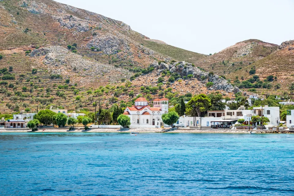Havnebyen Livadia på Tilos med kirken, hvide huse og terrasserede bjerge set fra vandet