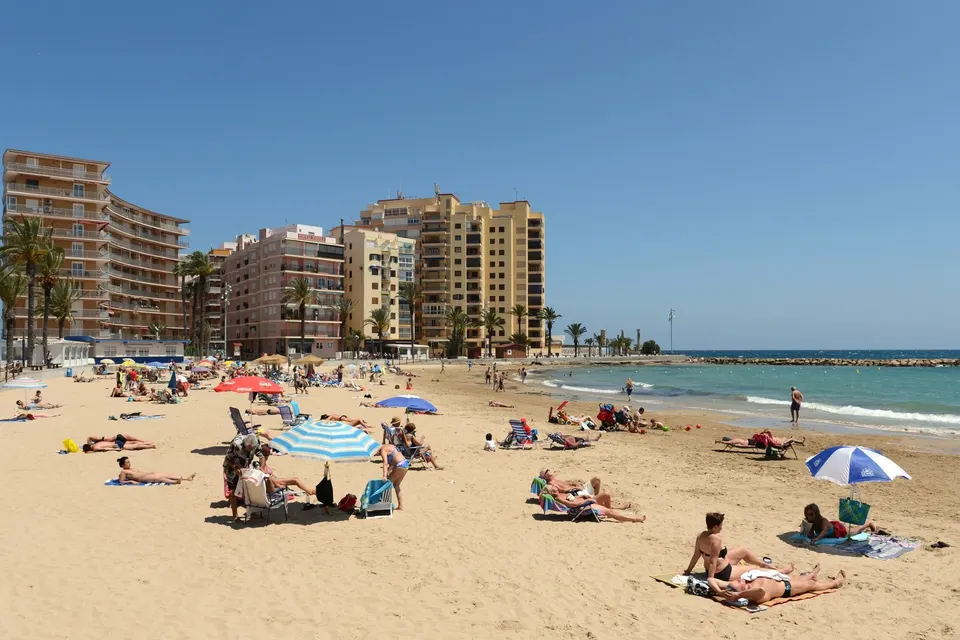 Badegæster på bystranden i Torrevieja foran husene