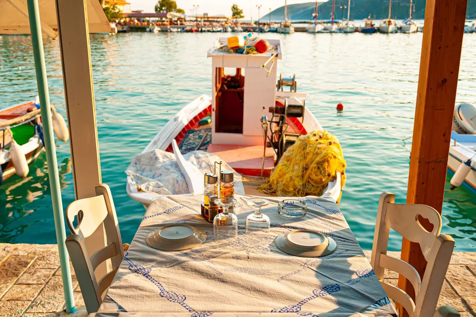 Tavernabord ved vandet i Vasiliki-bugten med en fiskerbåd